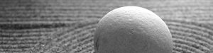 runder Stein im Vordergrund, Sand mit Muster im Hintergrund
