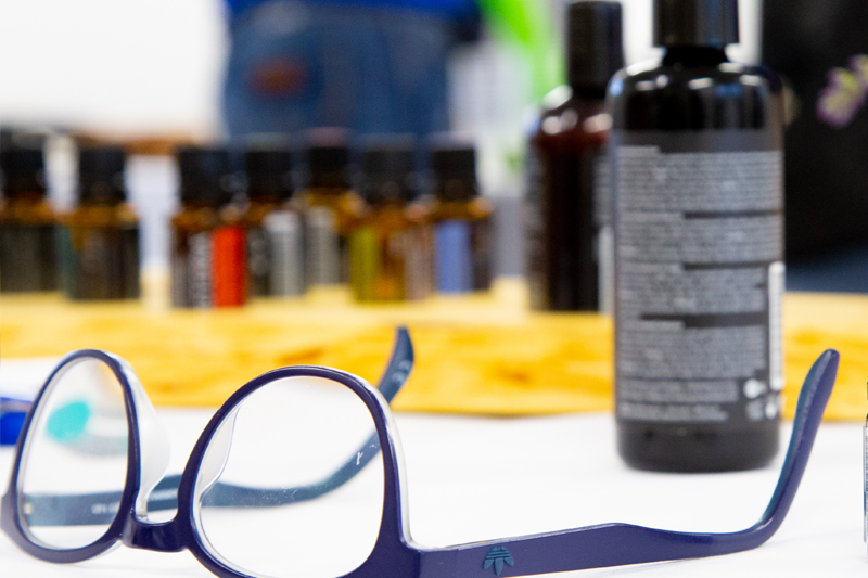 Brille vor unscharf abgebildetem Basisöl und kleinen Öl-Fläschchen