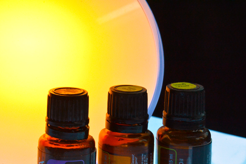 Drei Ölfläschen vor stimmungsvoller Lichtquelle